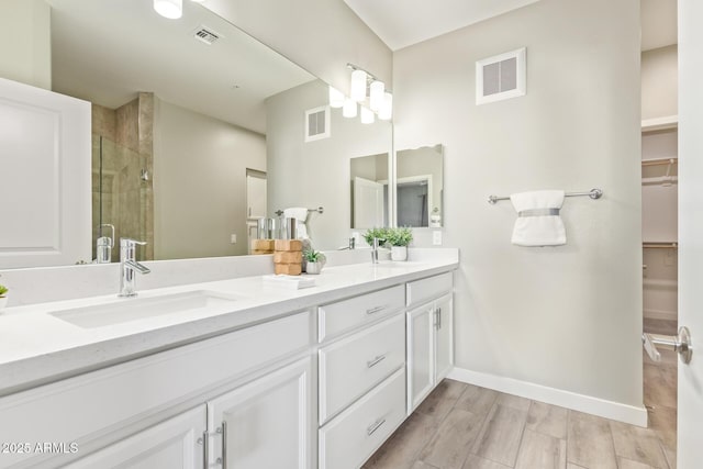 full bath featuring a stall shower, a sink, visible vents, and a walk in closet