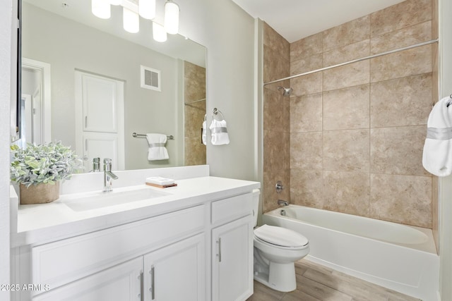 full bath with bathing tub / shower combination, visible vents, toilet, vanity, and wood finished floors