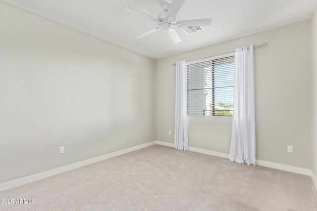 spare room featuring light carpet, ceiling fan, visible vents, and baseboards