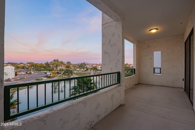 balcony at dusk featuring a water view