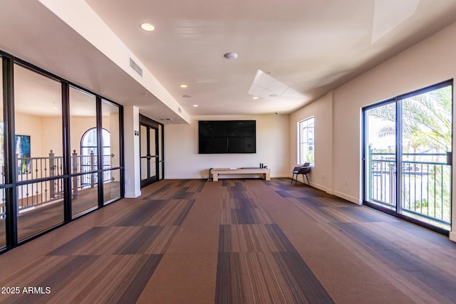 unfurnished living room with recessed lighting, dark carpet, visible vents, and baseboards