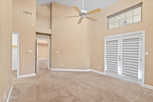 unfurnished living room with ceiling fan, high vaulted ceiling, and light carpet