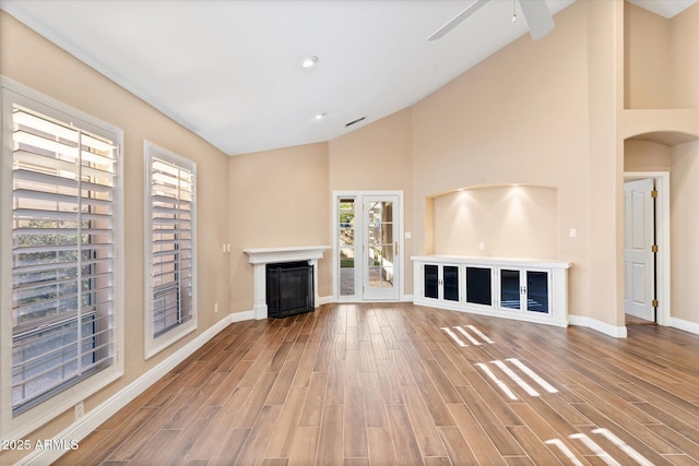 unfurnished living room with high vaulted ceiling, hardwood / wood-style floors, and ceiling fan