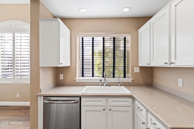 kitchen with sink, white cabinets, stainless steel dishwasher, and hardwood / wood-style floors