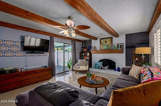 living room with a textured ceiling, light tile patterned flooring, ceiling fan, and a brick fireplace