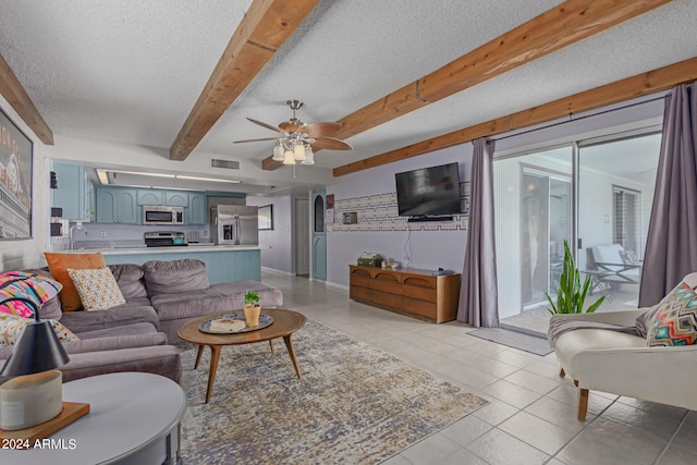 tiled living room featuring ceiling fan, beamed ceiling, and a textured ceiling