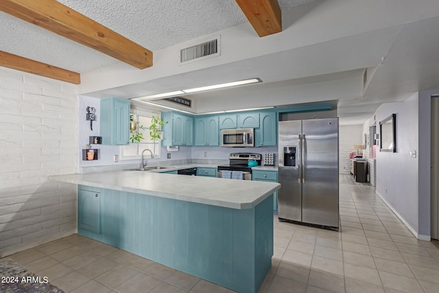 kitchen featuring blue cabinets, beam ceiling, kitchen peninsula, brick wall, and stainless steel appliances