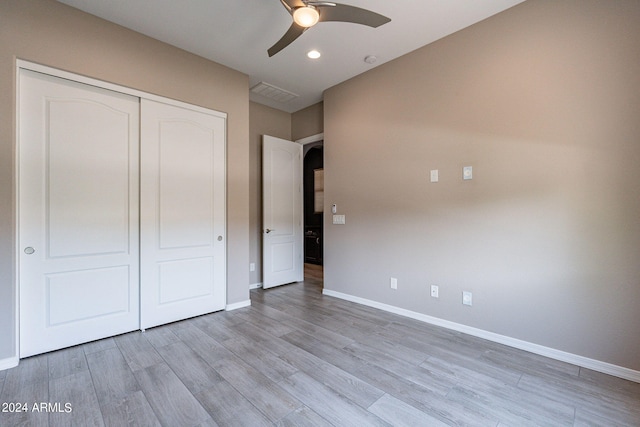 unfurnished bedroom featuring ceiling fan, light hardwood / wood-style floors, and a closet