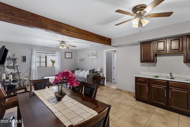 tiled dining space featuring beamed ceiling, ceiling fan, and sink