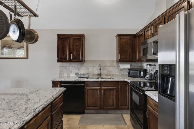 kitchen featuring light tile patterned flooring, sink, tasteful backsplash, light stone countertops, and black appliances