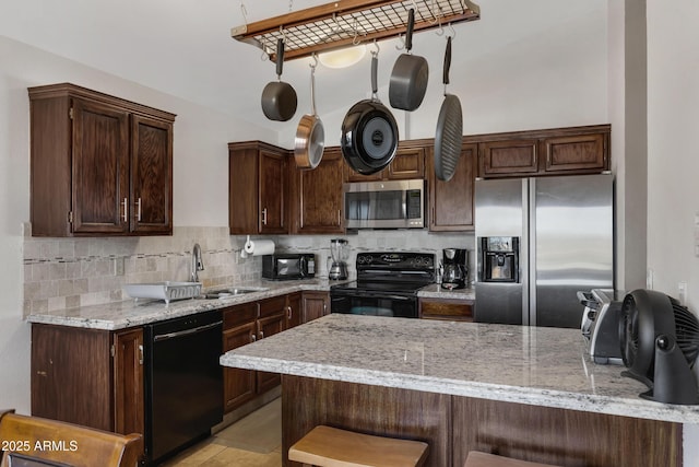 kitchen featuring backsplash, kitchen peninsula, light stone countertops, and black appliances