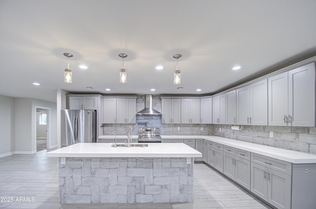 kitchen with stainless steel appliances, gray cabinets, a sink, and wall chimney exhaust hood