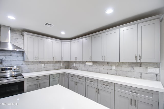 kitchen with visible vents, stainless steel range with electric cooktop, light countertops, gray cabinets, and wall chimney exhaust hood