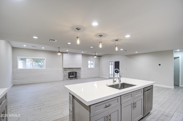 kitchen featuring a fireplace, gray cabinets, visible vents, a sink, and dishwasher