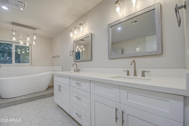 full bath featuring a freestanding tub, tile patterned flooring, a sink, and visible vents