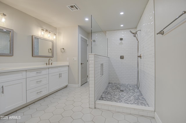 full bathroom featuring recessed lighting, visible vents, a tile shower, vanity, and baseboards