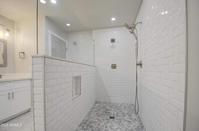 full bath featuring tile patterned floors, recessed lighting, a tile shower, and vanity