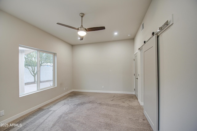 unfurnished room with visible vents, light carpet, baseboards, and a barn door