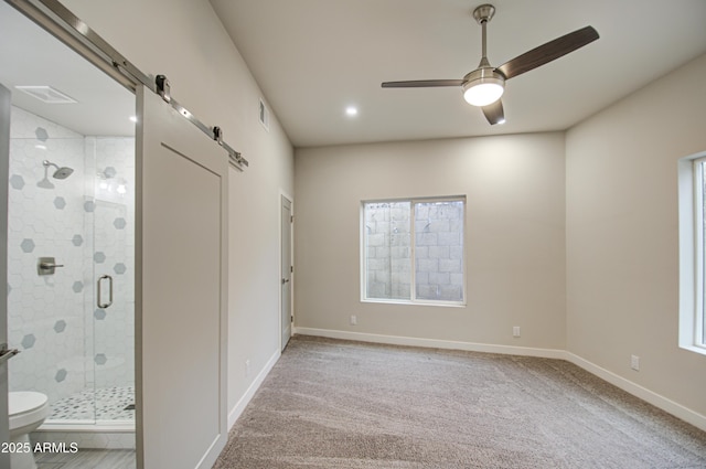 empty room featuring visible vents, ceiling fan, baseboards, and a barn door