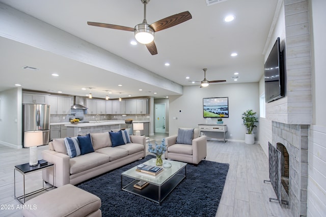 living room with a fireplace, recessed lighting, visible vents, light wood-style floors, and baseboards