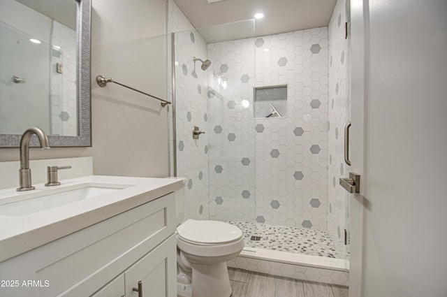 full bathroom with a stall shower, vanity, toilet, and wood finished floors