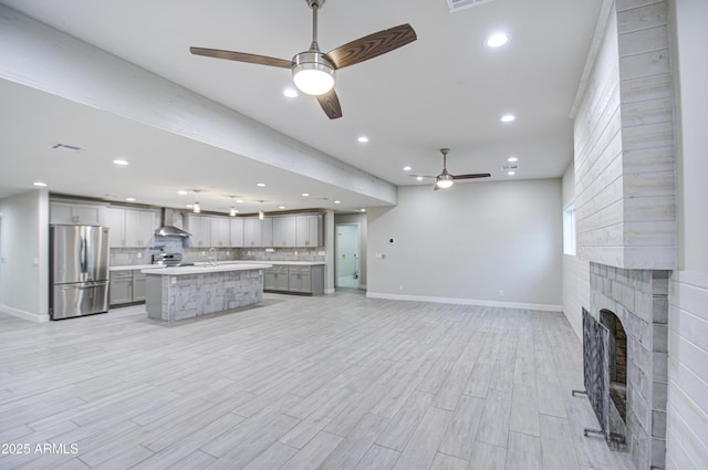 unfurnished living room with a fireplace, recessed lighting, light wood-style flooring, a sink, and ceiling fan