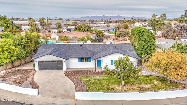 view of front facade with a mountain view, a garage, fence, concrete driveway, and stucco siding