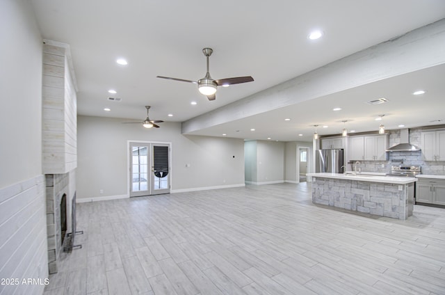 unfurnished living room with light wood-style floors, recessed lighting, and a large fireplace