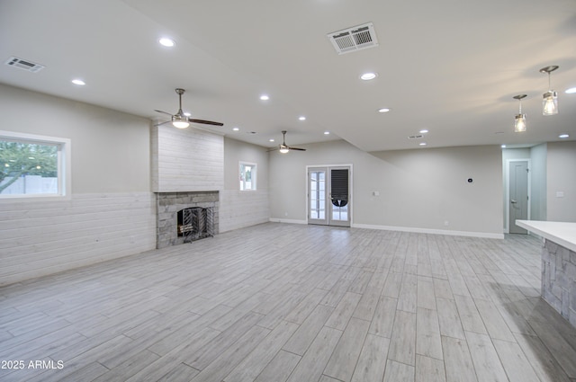 unfurnished living room with light wood-style flooring, a fireplace, and visible vents