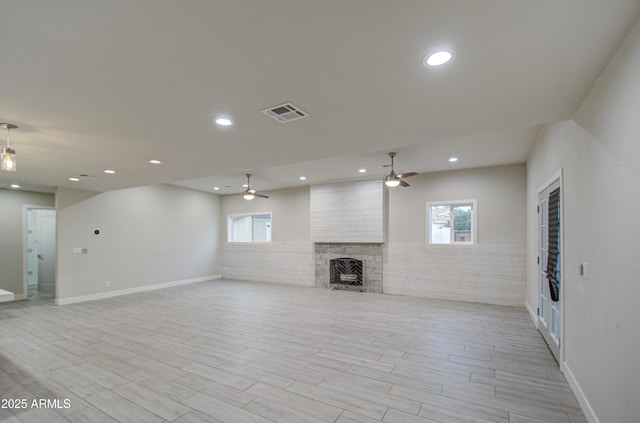 unfurnished living room with a large fireplace, wood tiled floor, visible vents, and recessed lighting