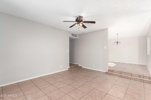empty room featuring ceiling fan, light tile patterned floors, a textured ceiling, and baseboards