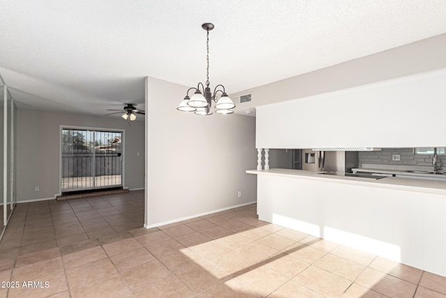 unfurnished dining area featuring ceiling fan, light tile patterned flooring, a chandelier, a sink, and baseboards