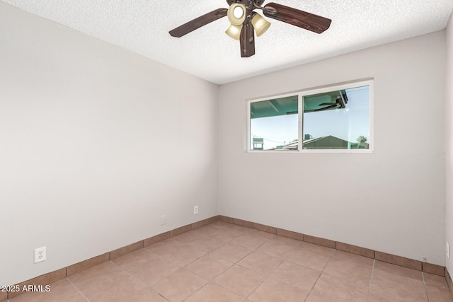 empty room with a textured ceiling, a ceiling fan, baseboards, and light tile patterned floors