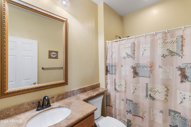 bathroom with toilet, vanity, and curtained shower