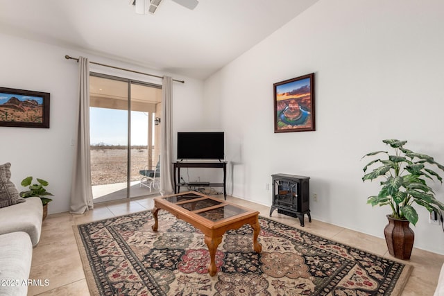 living area featuring light tile patterned floors, ceiling fan, lofted ceiling, and a wood stove