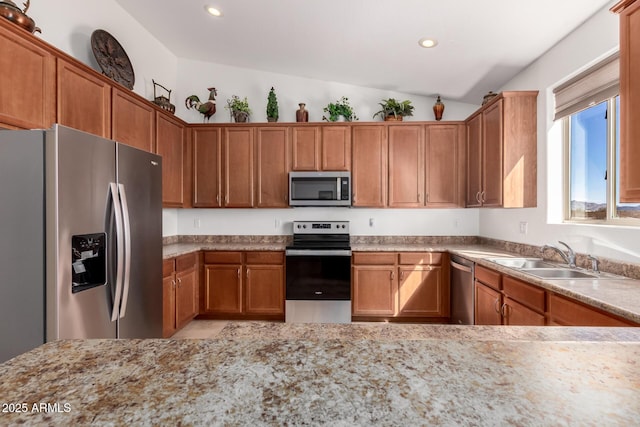 kitchen with recessed lighting, appliances with stainless steel finishes, brown cabinetry, vaulted ceiling, and a sink