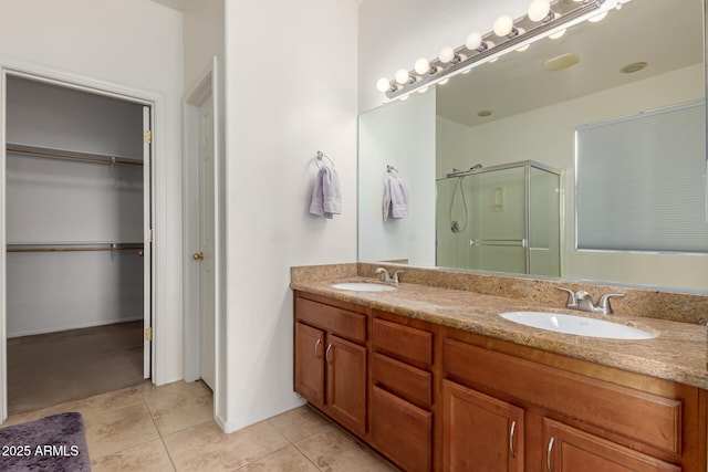 full bathroom featuring a stall shower, tile patterned flooring, a spacious closet, and a sink