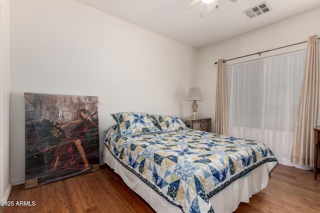 bedroom featuring ceiling fan, visible vents, and wood finished floors