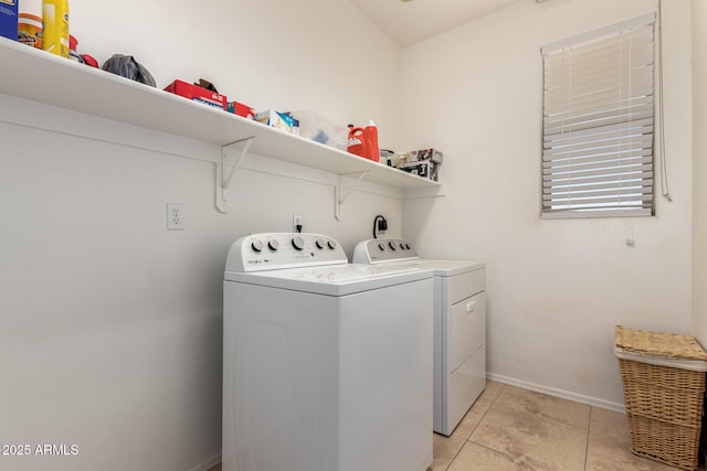 laundry area featuring light tile patterned floors, laundry area, washer and clothes dryer, and baseboards