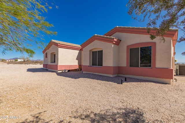 view of home's exterior featuring central air condition unit, a tile roof, and stucco siding