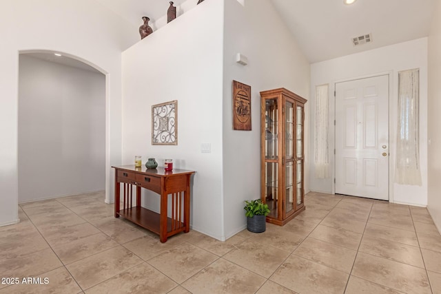 hall featuring arched walkways, recessed lighting, visible vents, high vaulted ceiling, and tile patterned floors