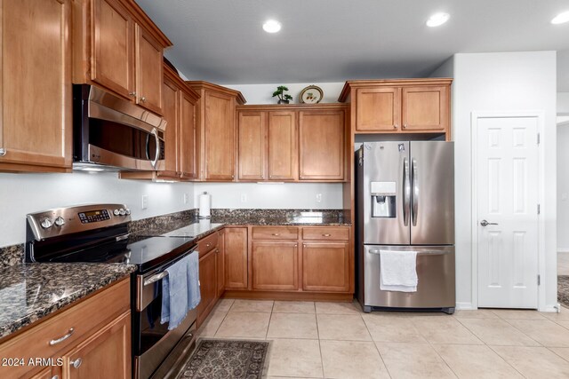 kitchen featuring dark stone countertops, light tile patterned floors, and appliances with stainless steel finishes