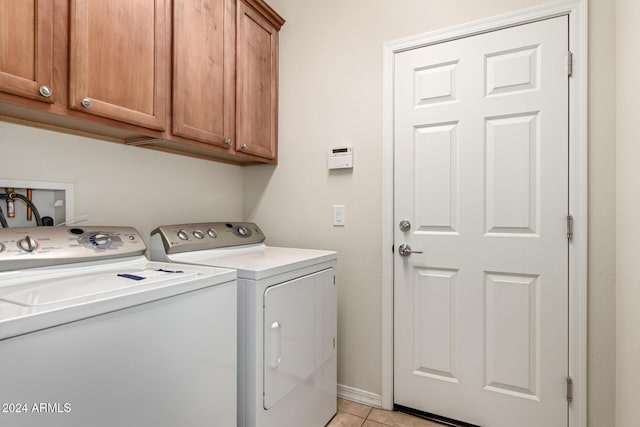 clothes washing area featuring cabinets, washing machine and dryer, and light tile patterned flooring