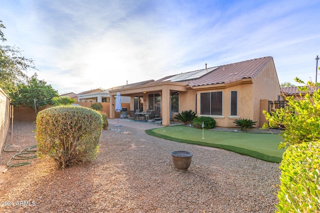 rear view of property featuring solar panels and a patio area