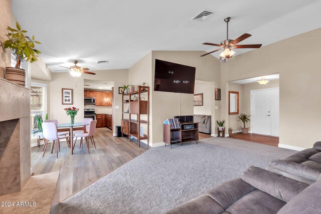 living room featuring lofted ceiling, ceiling fan, and light hardwood / wood-style flooring