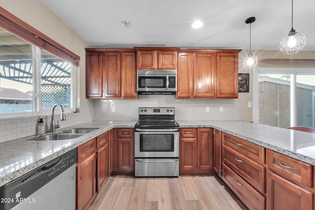 kitchen featuring stainless steel appliances, a wealth of natural light, pendant lighting, and light hardwood / wood-style flooring