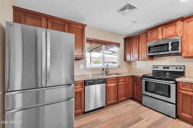 kitchen featuring light hardwood / wood-style floors, stainless steel appliances, sink, and light stone counters