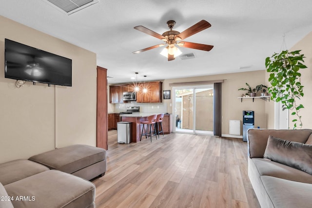 living room with ceiling fan and light hardwood / wood-style flooring