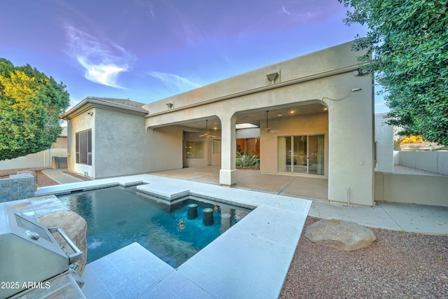 back house at dusk featuring a patio and ceiling fan