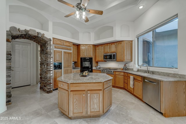 kitchen with sink, ceiling fan, appliances with stainless steel finishes, a towering ceiling, and a center island